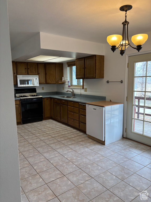 Kitchen with light tile patterned flooring, a notable chandelier, white appliances, a sink, and hanging light fixtures