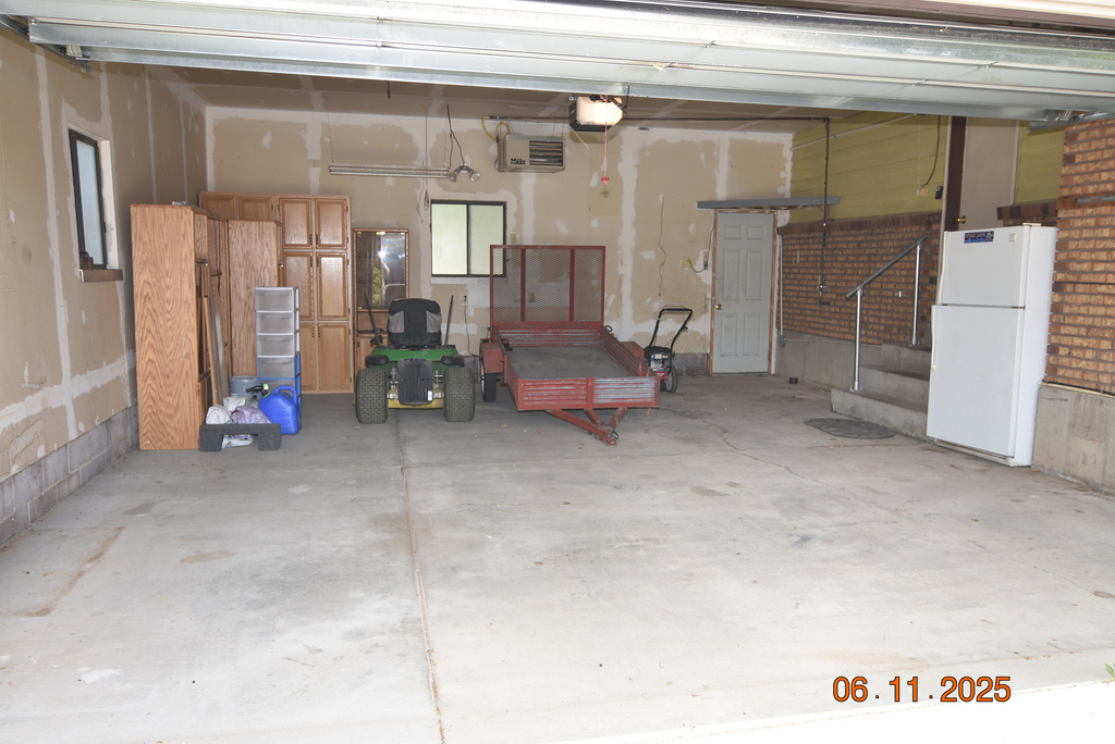 Garage with freestanding refrigerator and a garage door opener