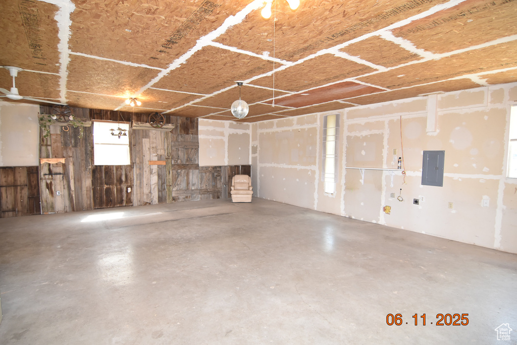 Garage featuring electric panel and wooden walls