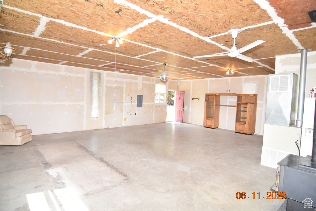 Garage with a wood stove, electric panel, and ceiling fan