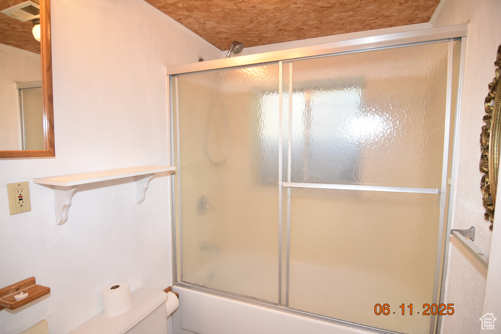 Bathroom featuring toilet and combined bath / shower with glass door