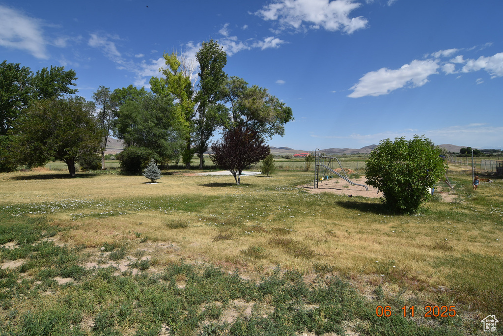 View of green lawn with a mountain view and a view of rural / pastoral area