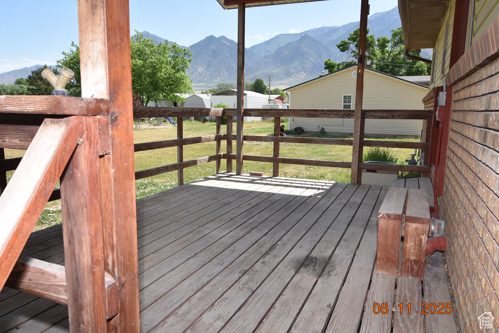 Deck with a mountain view and a lawn