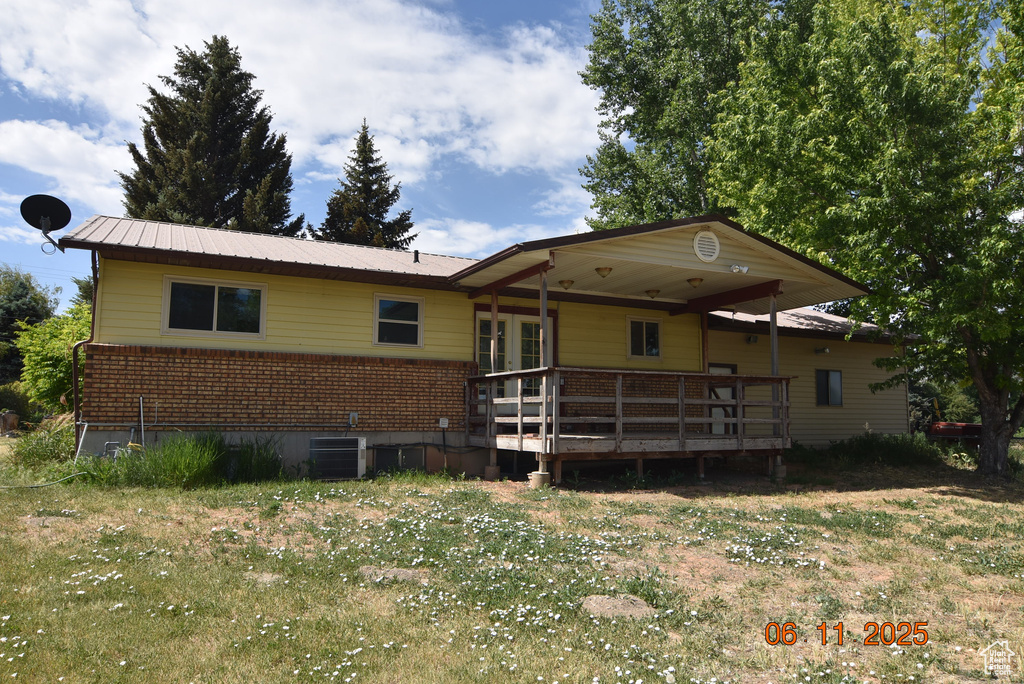 Rear view of property with brick siding, a deck, french doors, and a metal roof