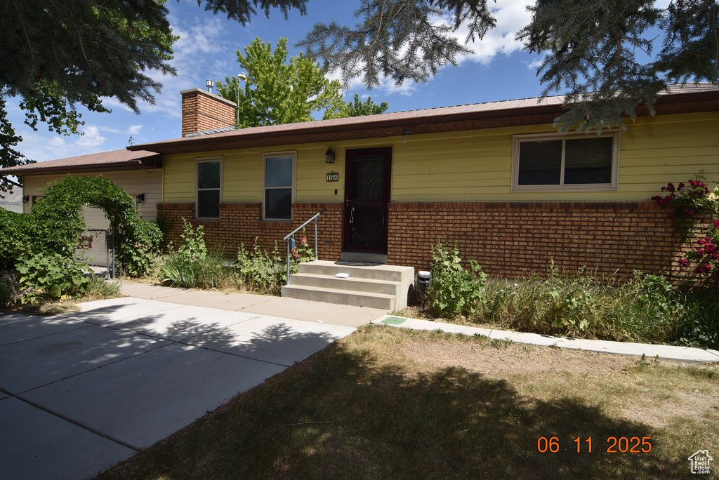 Single story home featuring a chimney and brick siding