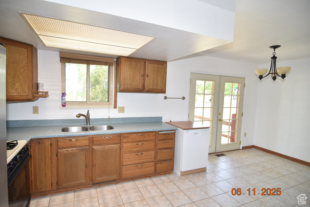 Kitchen featuring gas range, dishwasher, brown cabinets, and light tile patterned flooring
