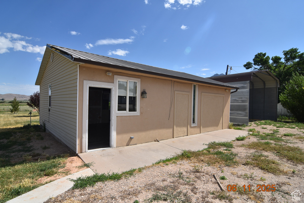 Back of house featuring stucco siding and a metal roof