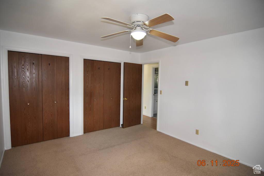 Unfurnished bedroom with multiple closets, carpet flooring, and a ceiling fan