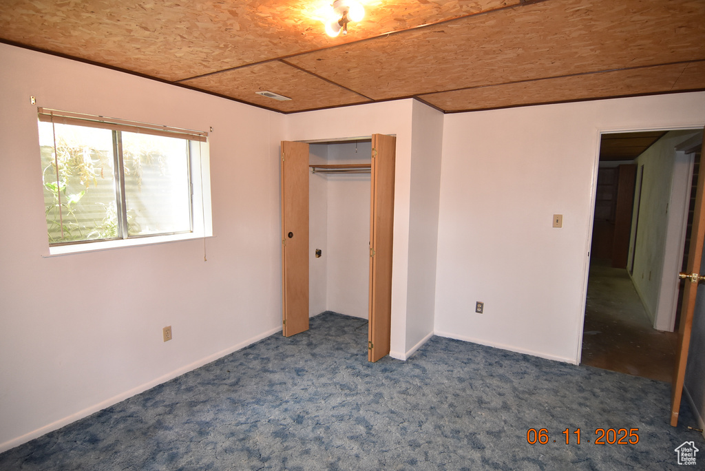 Unfurnished bedroom with dark colored carpet and a closet