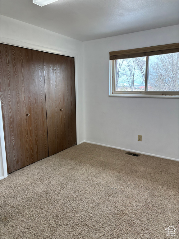 Unfurnished bedroom with a closet, carpet flooring, and visible vents