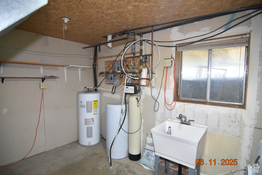 Utilities featuring electric water heater and a sink