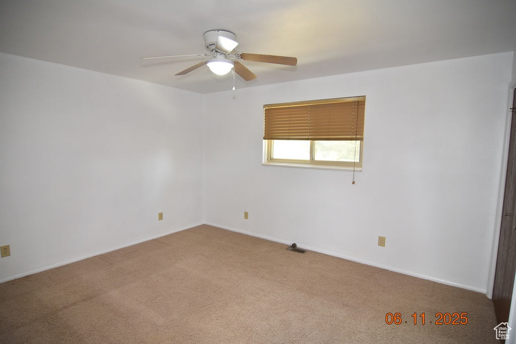 Carpeted empty room featuring a ceiling fan and baseboards