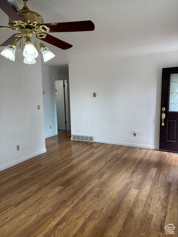 Empty room featuring a ceiling fan, baseboards, visible vents, and wood finished floors