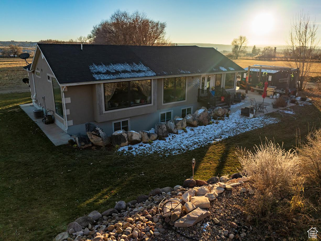 Back house at dusk featuring a patio area and a lawn