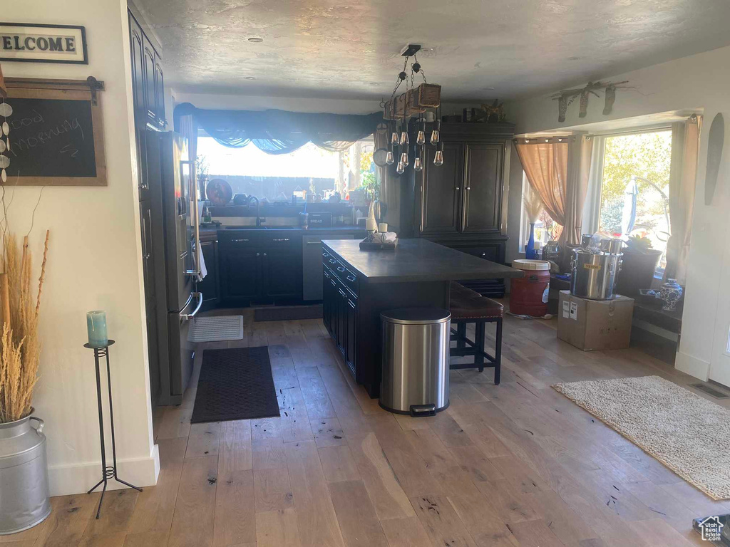 Kitchen featuring a kitchen bar, a center island, light hardwood / wood-style floors, and sink