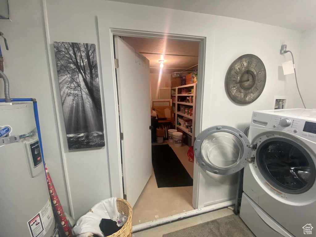 Laundry room featuring water heater and washer / dryer