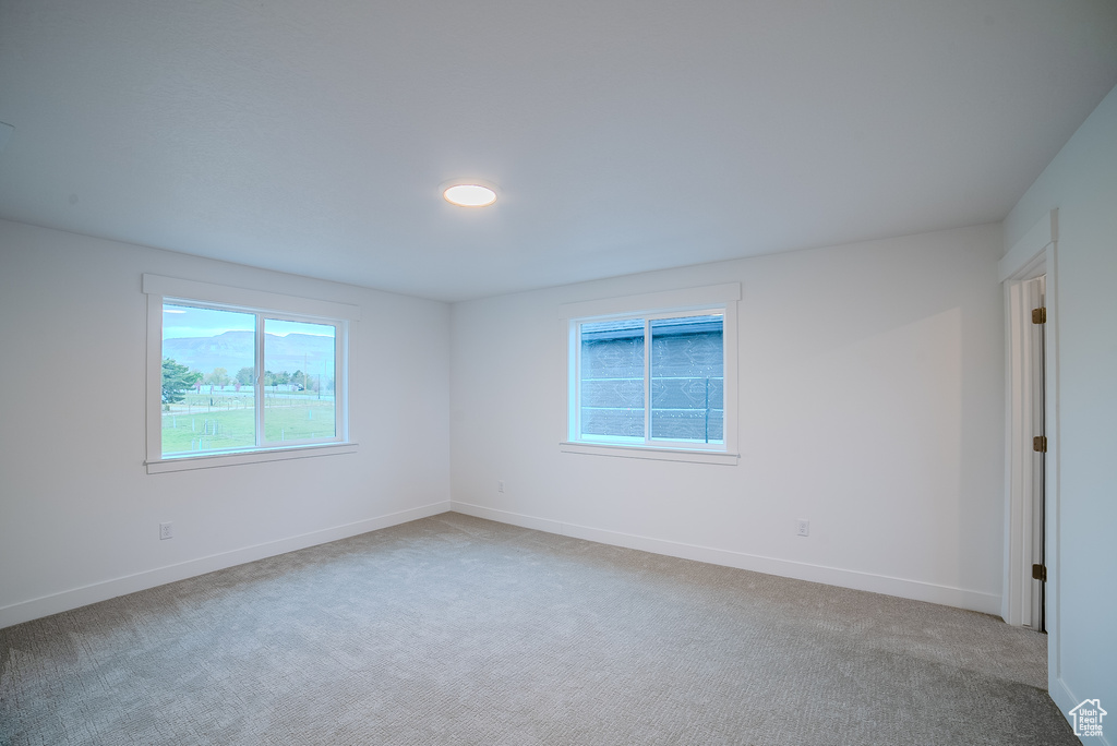 Unfurnished room with light colored carpet and baseboards