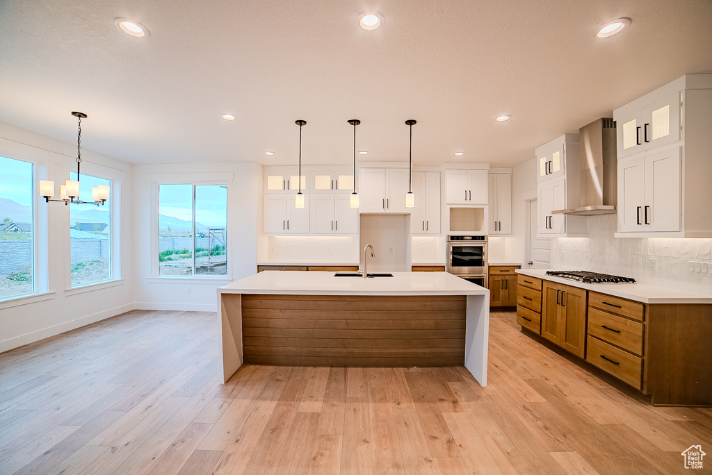 Kitchen featuring recessed lighting, stainless steel oven, a sink, wall chimney range hood, and tasteful backsplash