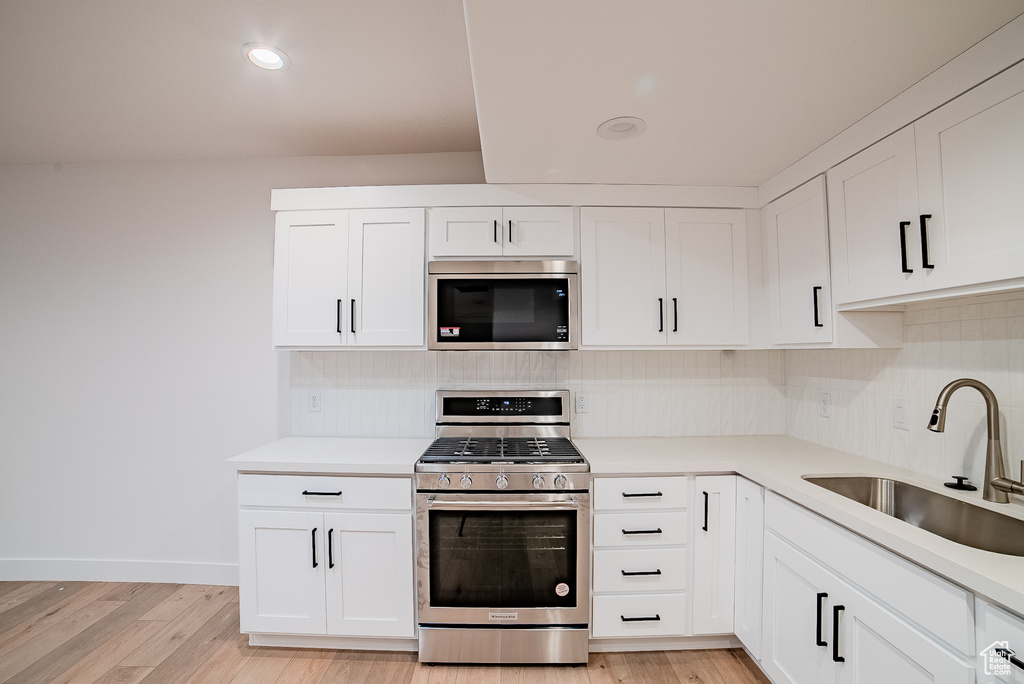 Kitchen featuring a sink, light wood finished floors, stainless steel appliances, and backsplash