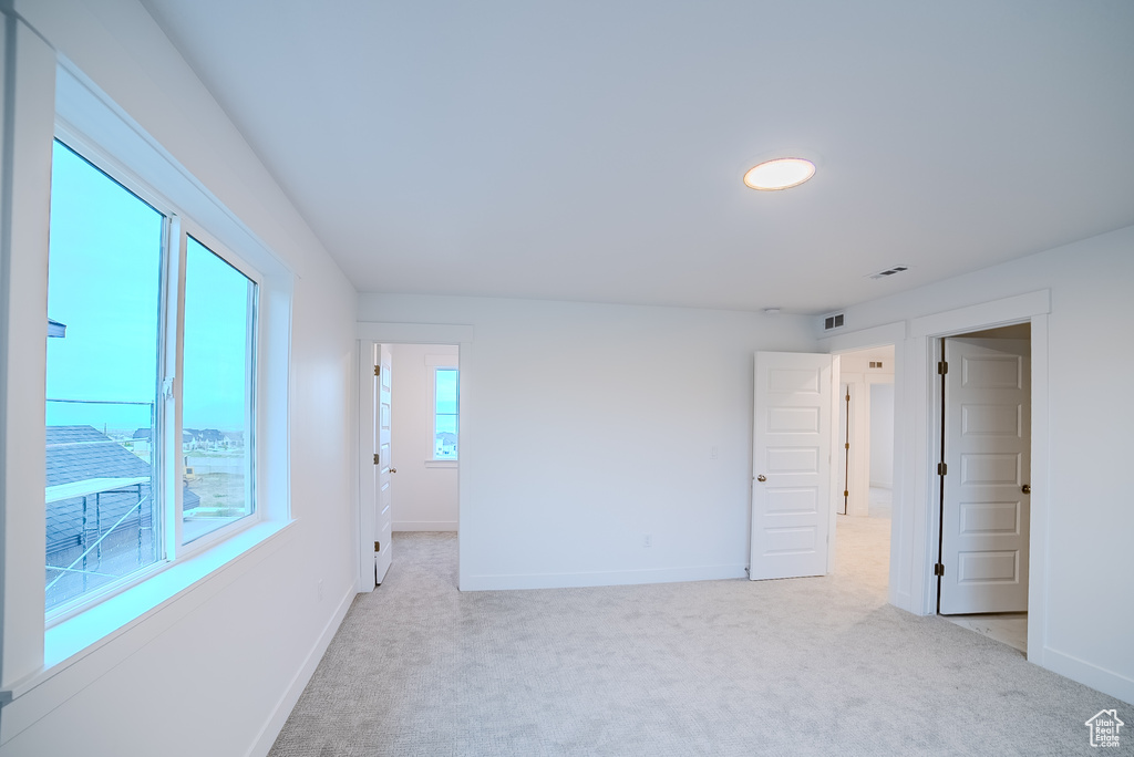 Empty room featuring light carpet, baseboards, and visible vents