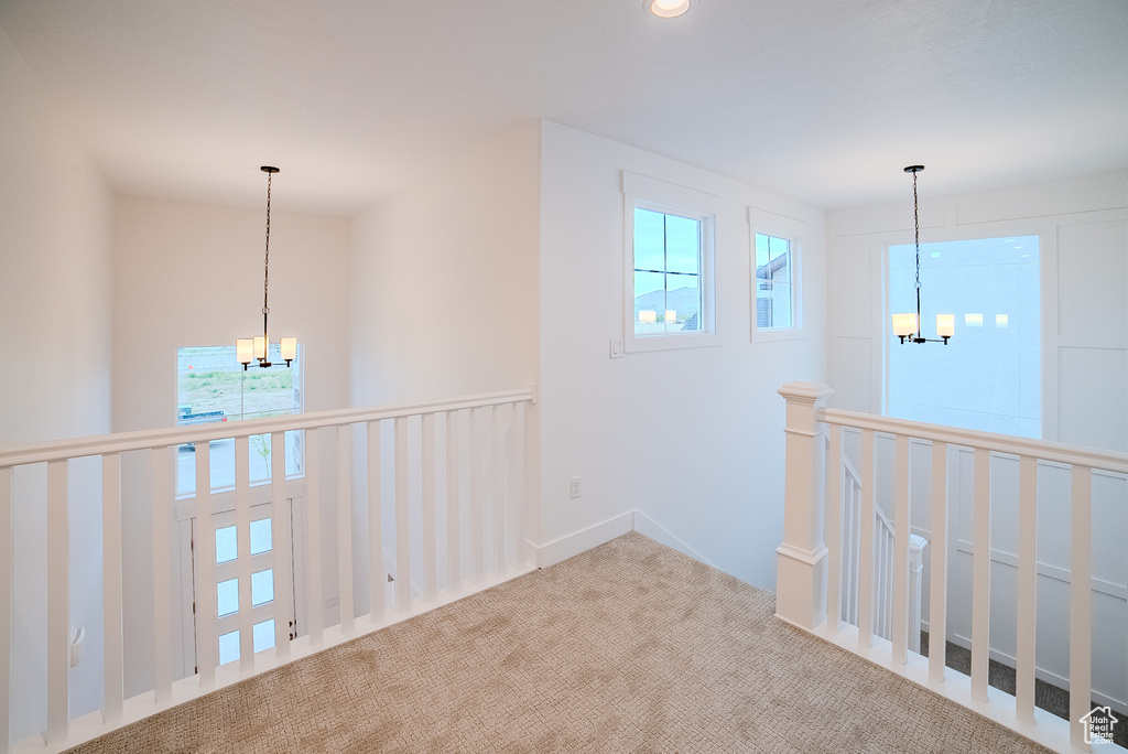 Hallway featuring a chandelier, an upstairs landing, and carpet floors