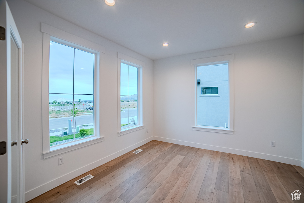 Empty room featuring light wood finished floors, baseboards, visible vents, and recessed lighting