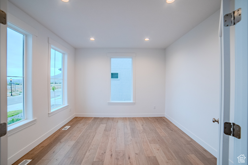 Empty room with light wood-style flooring, baseboards, visible vents, and recessed lighting