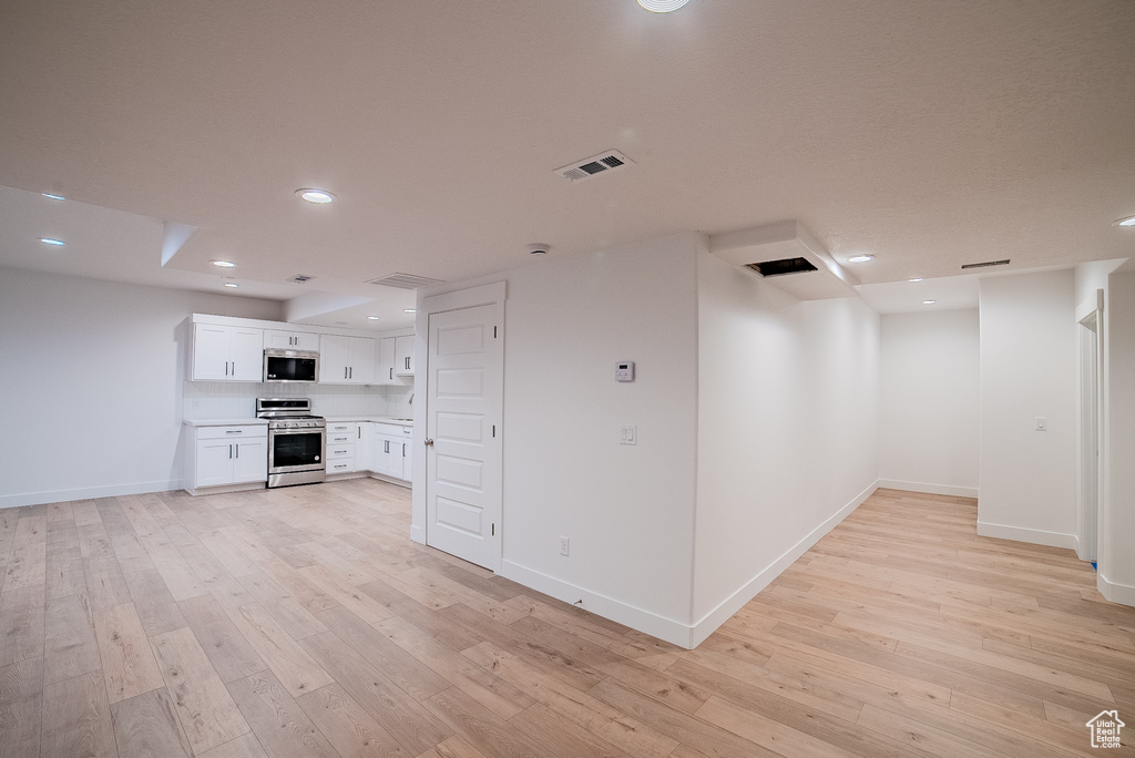 Interior space with light wood-style flooring, baseboards, visible vents, and recessed lighting