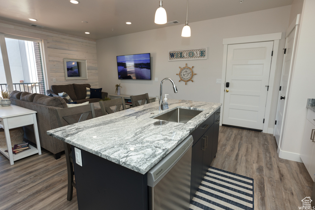 Kitchen with sink, dark hardwood / wood-style flooring, stainless steel dishwasher, pendant lighting, and a kitchen island with sink