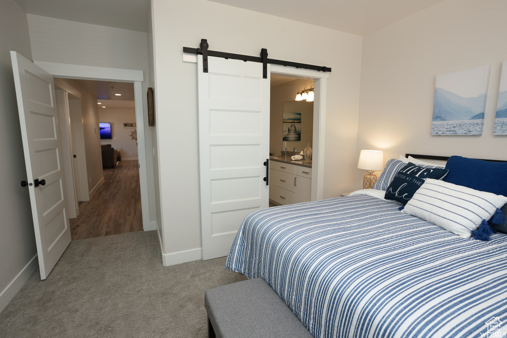 Carpeted bedroom with connected bathroom and a barn door