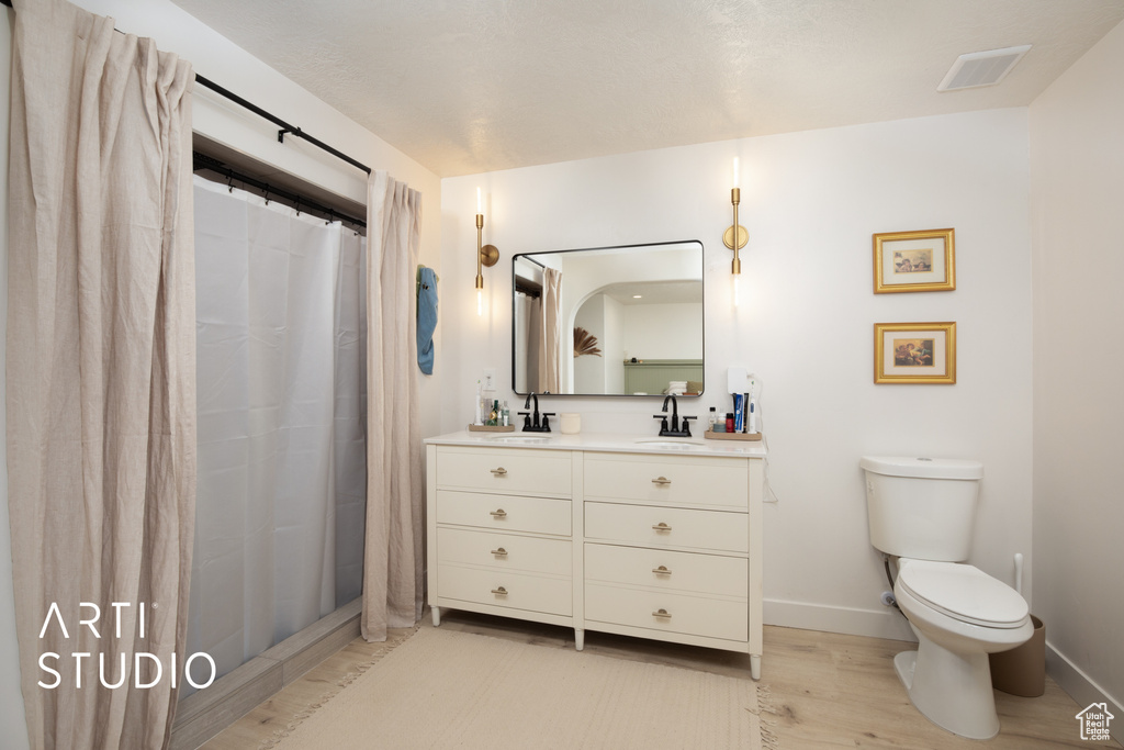 Bathroom with hardwood / wood-style flooring, vanity, toilet, and a shower with shower curtain