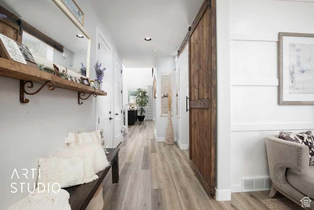 Hall featuring a barn door, light hardwood / wood-style flooring, and a wealth of natural light