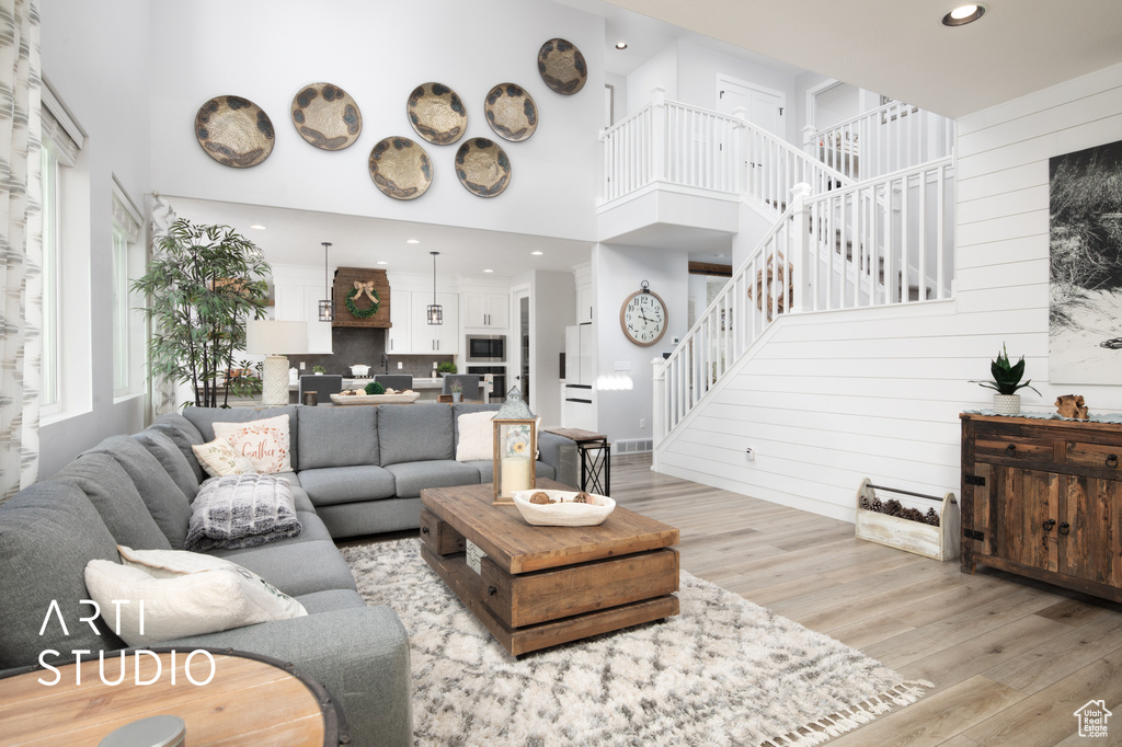 Living room featuring wooden walls, a towering ceiling, and light hardwood / wood-style floors