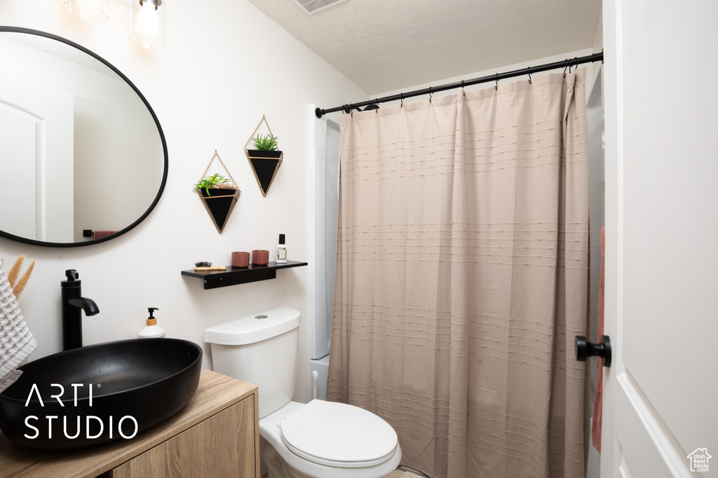 Bathroom with a textured ceiling, toilet, and sink