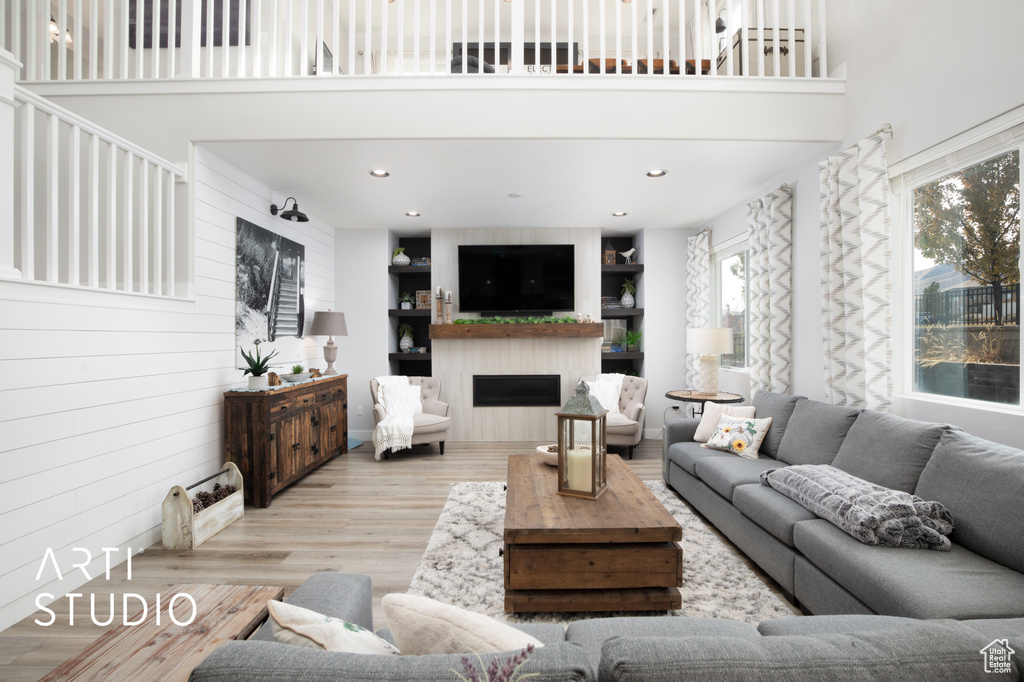 Living room featuring a high ceiling, light wood-type flooring, and wooden walls