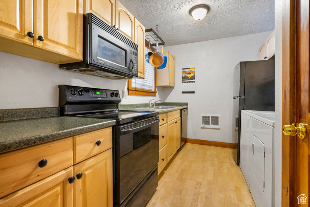 Kitchen featuring light wood-type flooring, a textured ceiling, sink, black appliances, and washing machine and clothes dryer