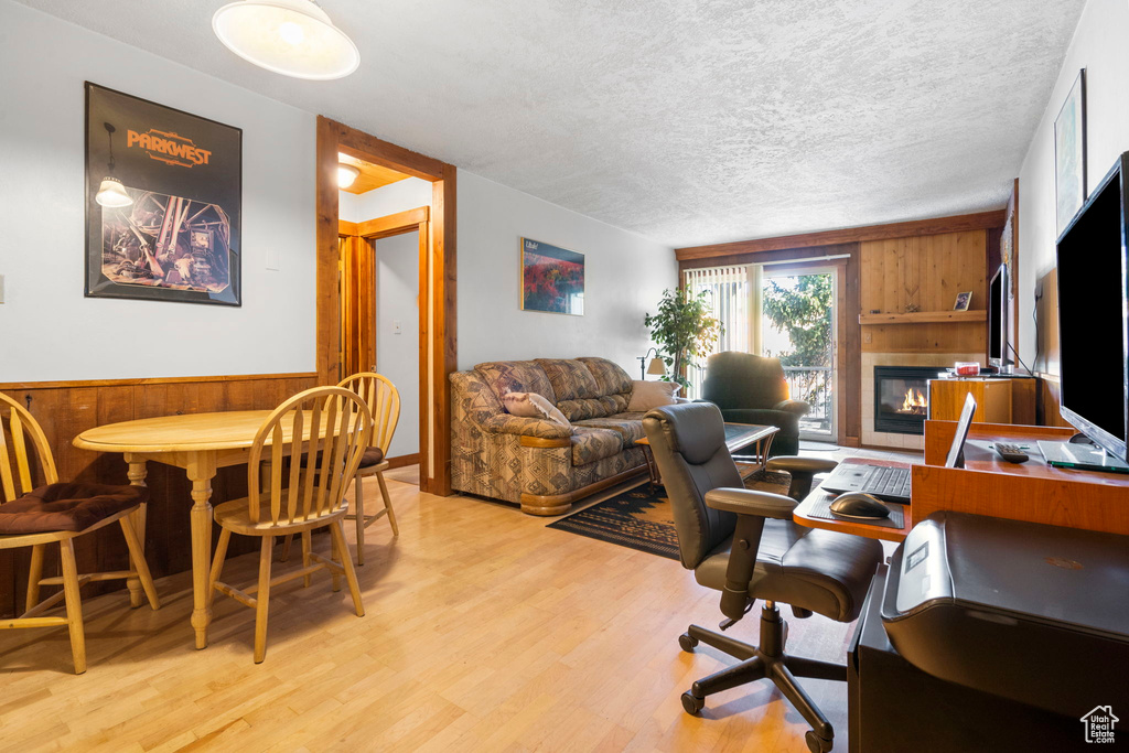 Office area with a textured ceiling, light hardwood / wood-style floors, and wood walls