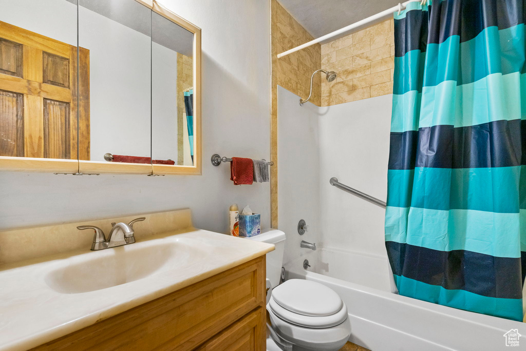 Full bathroom featuring shower / bath combo with shower curtain, vanity, and toilet