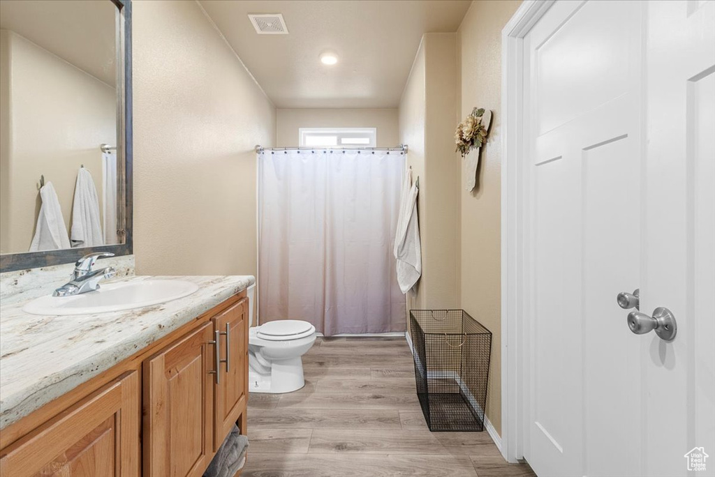 Bathroom with a shower with curtain, hardwood / wood-style floors, vanity, and toilet