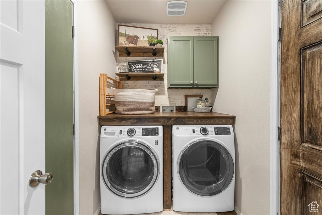 Laundry area featuring washing machine and dryer and cabinets