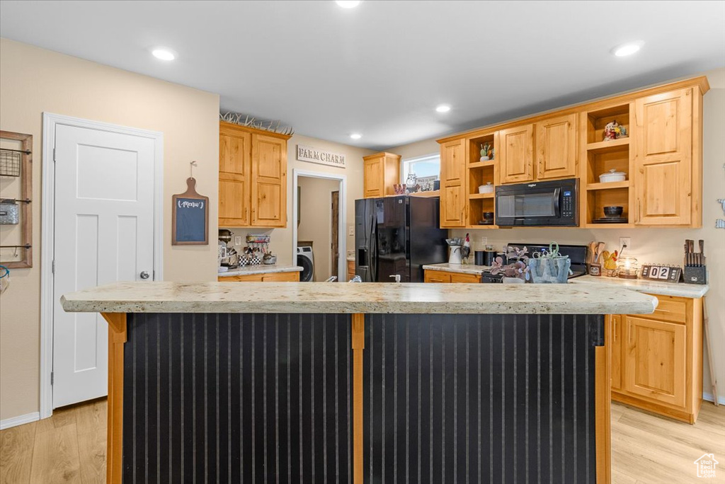 Kitchen with black appliances, a center island, light hardwood / wood-style floors, and light brown cabinets