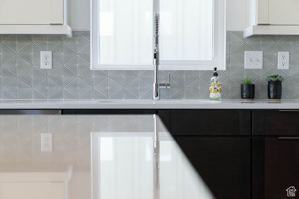 Kitchen featuring tasteful backsplash and white cabinetry