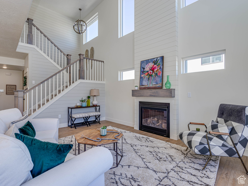Living room with stairway, baseboards, a large fireplace, a high ceiling, and wood finished floors