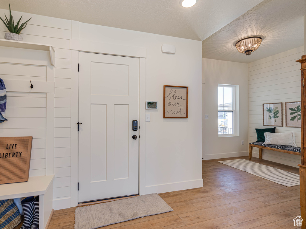 Entrance foyer with baseboards, light wood-type flooring, and a textured ceiling