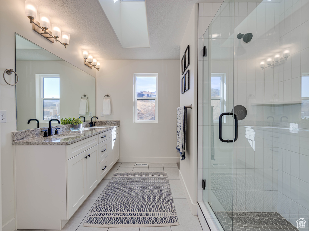 Full bathroom with double vanity, a sink, tile patterned flooring, and plenty of natural light