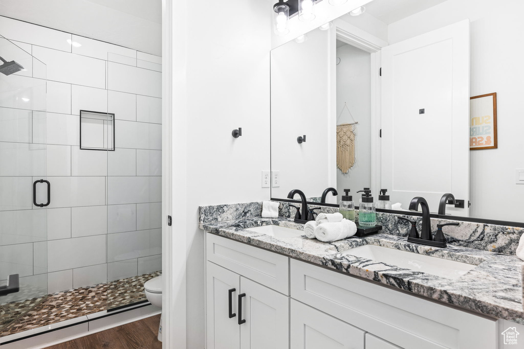 Bathroom with a baseboard heating unit, toilet, a shower with door, vanity, and hardwood / wood-style flooring
