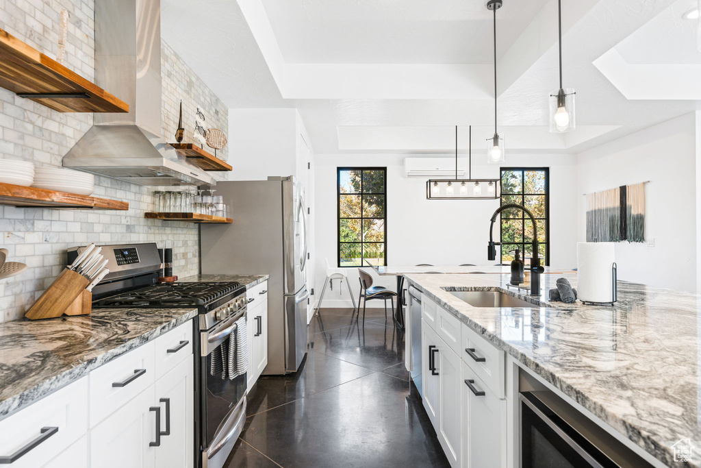 Kitchen featuring sink, decorative backsplash, white cabinetry, stainless steel appliances, and a wall unit AC