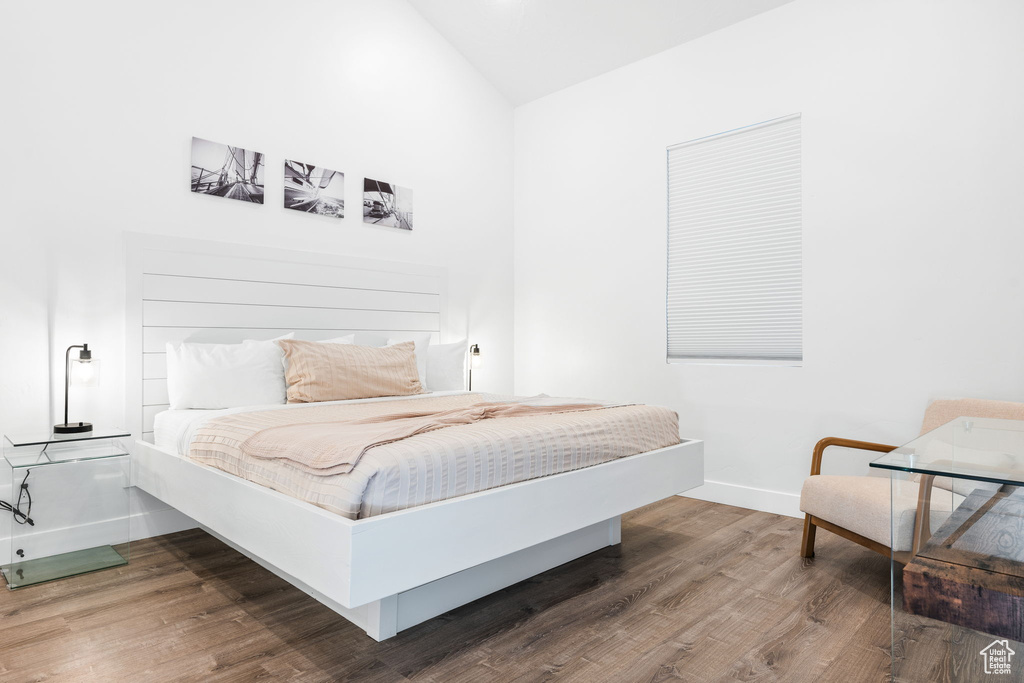 Bedroom with hardwood / wood-style floors and lofted ceiling