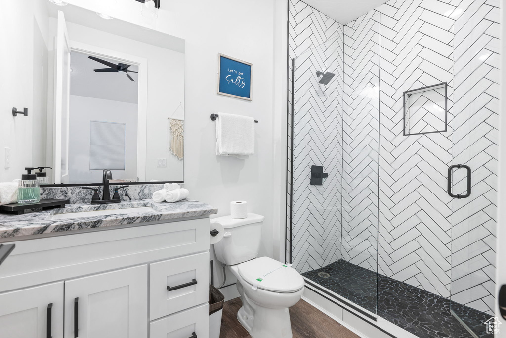 Bathroom featuring ceiling fan, hardwood / wood-style floors, an enclosed shower, toilet, and vanity