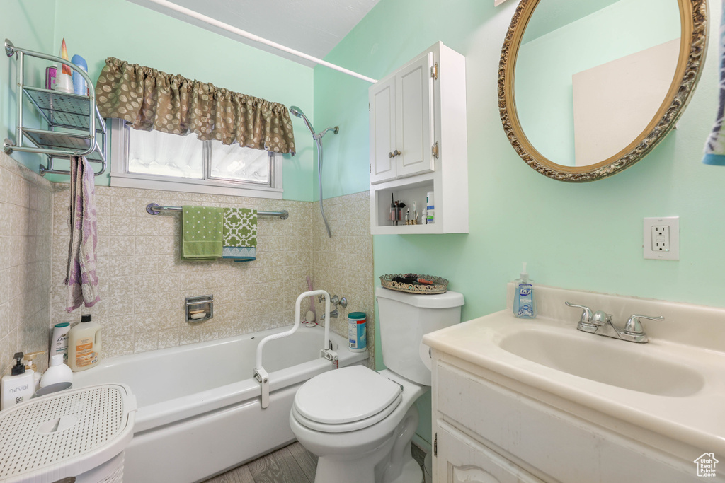 Full bathroom with toilet, vanity, wood-type flooring, and tiled shower / bath